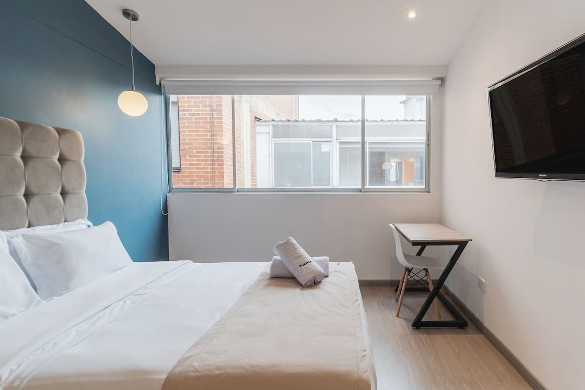 Une chambre d’hôtel moderne équipée d’un lit, d’un bureau et d’une télévision.