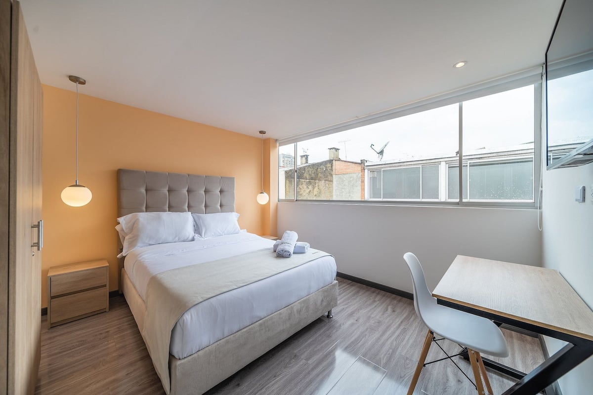 Une chambre moderne avec un lit, une table de chevet et un bureau avec une chaise.