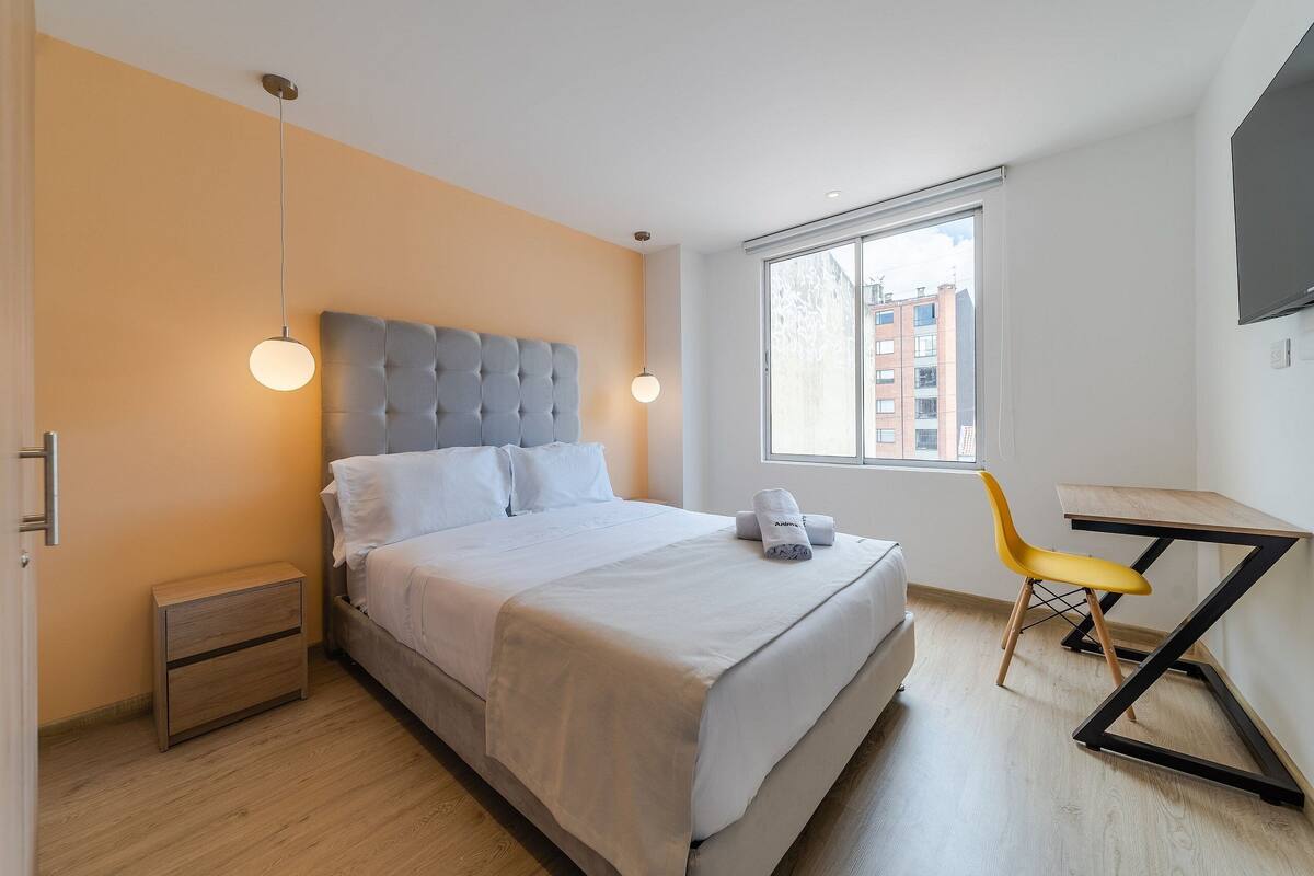 Une chambre d’hôtel moderne équipée d’un lit, d’une table de chevet et d’un bureau avec une chaise.