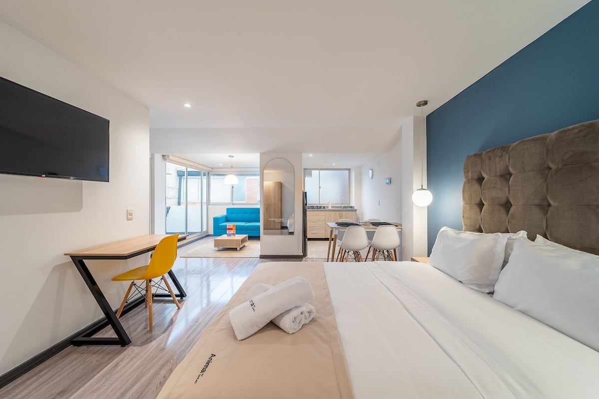 Une chambre d’hôtel avec un lit, un bureau, une chaise et un téléviseur.