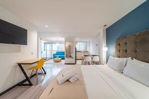 A hotel room with a bed, a desk, a chair, and a TV.