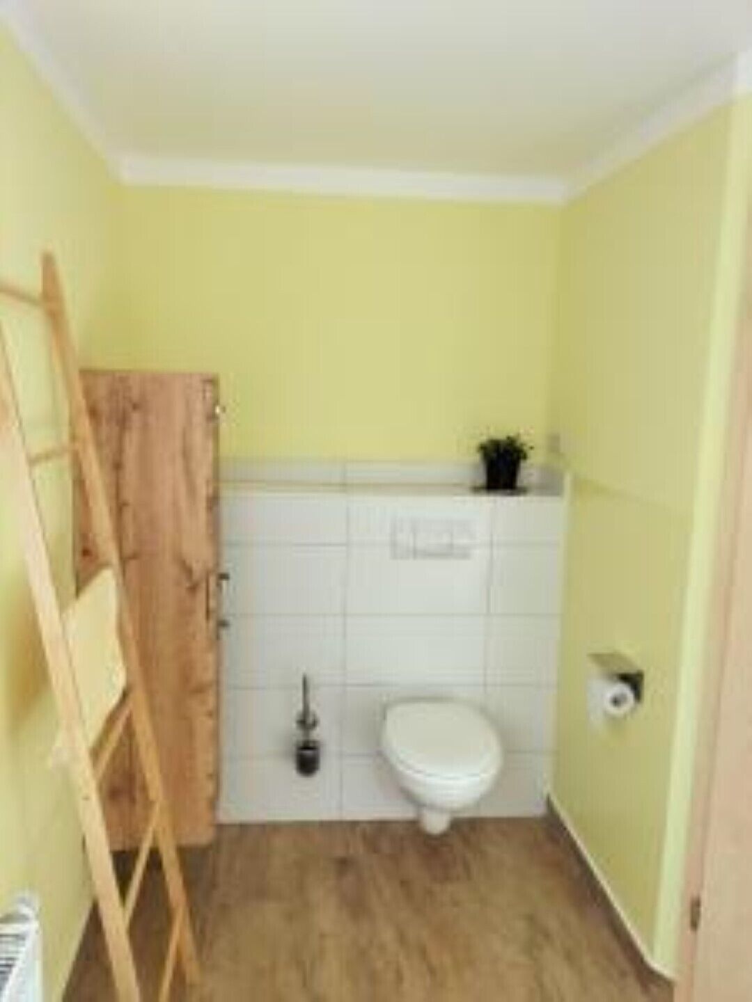 Un baño pequeño con un inodoro, una escalera de madera y un lavamanos blanco.
