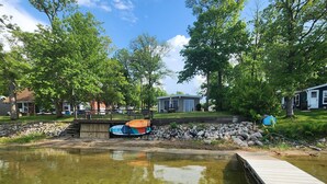 A clear pond with a wooden dock, surrounded by trees and a small building. - Lake Front, Pontoon, Bunk House (Rochert)