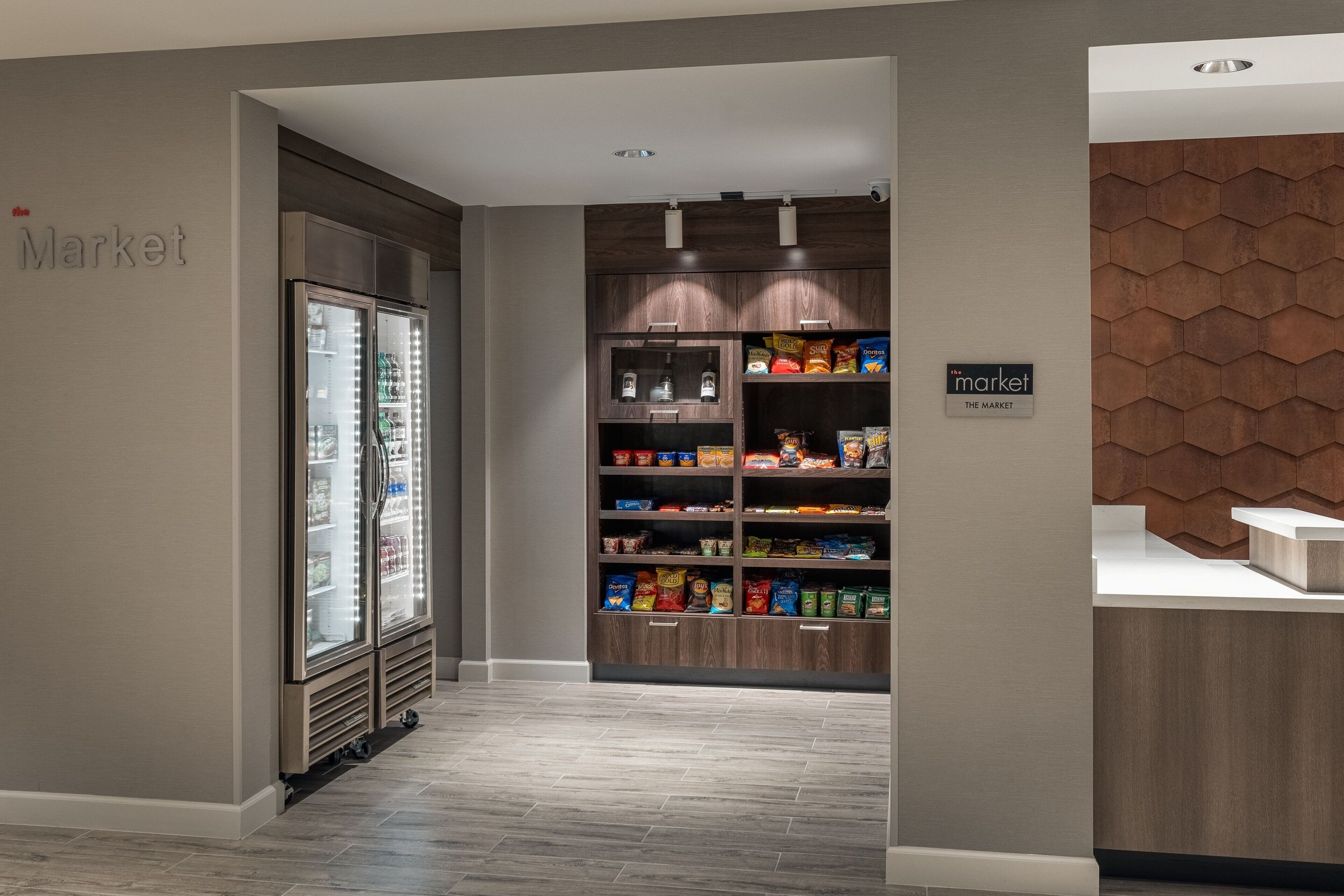A modern retail area with a refrigerated display and a variety of snack products on shelves.