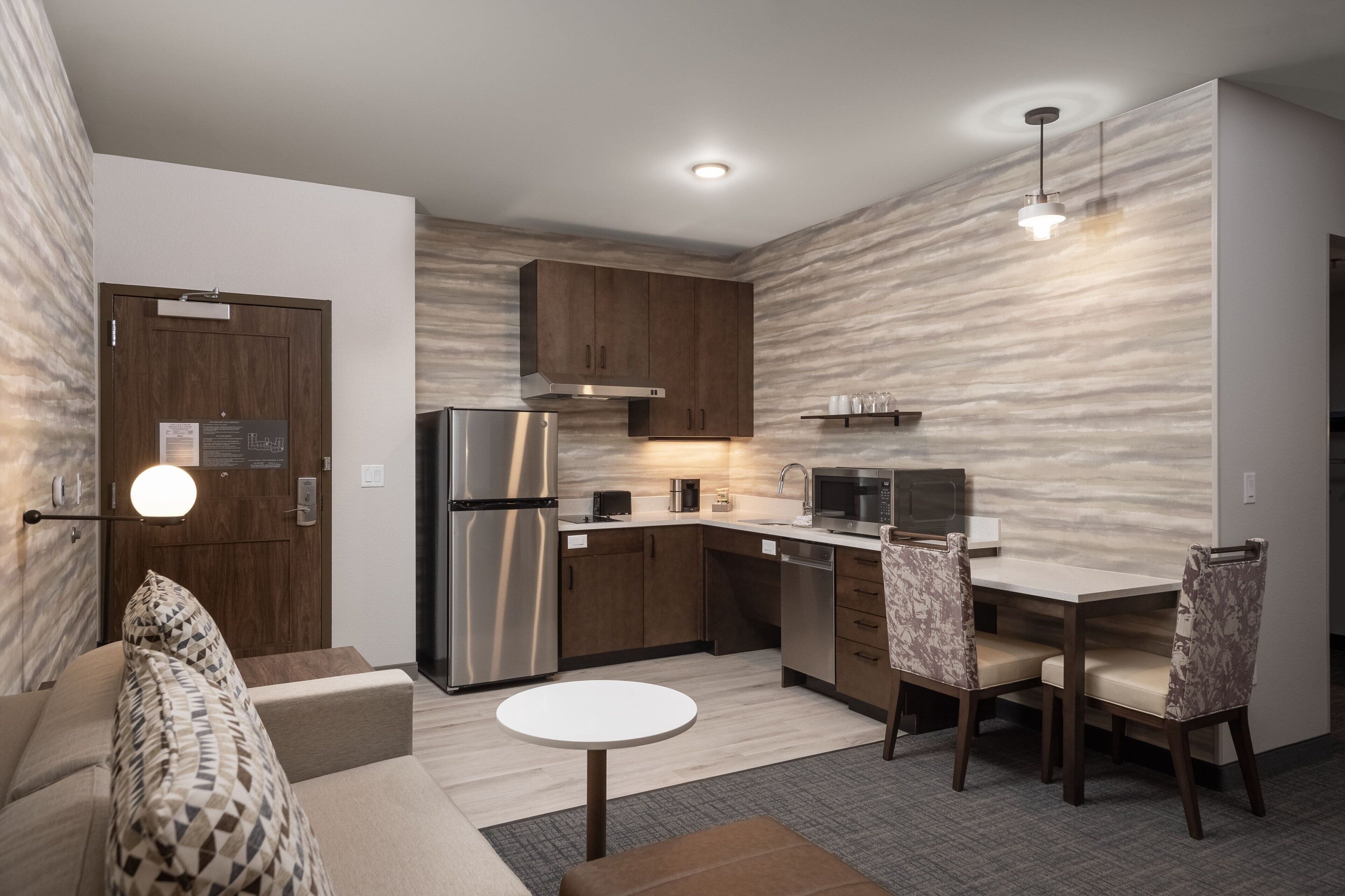 A compact kitchen with modern appliances, a dining area with two chairs, and a small round table.