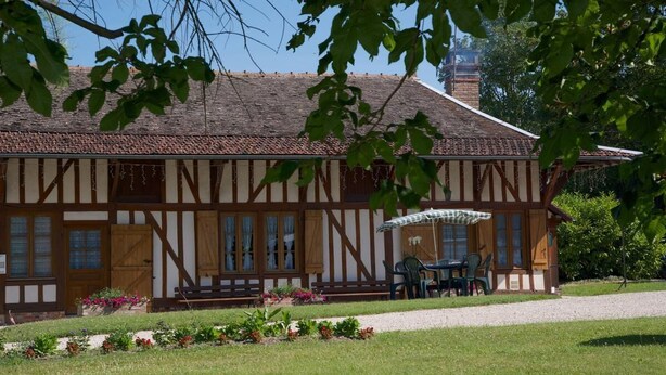 A traditional half-timbered building with a covered outdoor seating area and a gravel path leading to it. - Les Rosiers - ONJON - Gîte (ONJON)