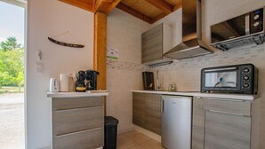 Kompakti keittiö, jossa on työtasolla mikroaaltouuni, leivänpaahdin ja kahvinkeitin, sekä astianpesukone ja roskakori.