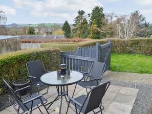 Eine Terrasse im Freien mit einem runden Tisch und Stühlen, einer Kaffeemaschine und Blick auf die Landschaft.
