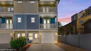 A multi-story residential building with balconies, a garage, and a landscaped front yard. - Townhome Steps to the Beach-Hot Tub, Private Yard (Jacksonville Beach)