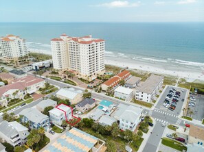 Zona residencial costera con propiedades frente a la playa, incluyendo un hotel grande con varios pisos y un estacionamiento.