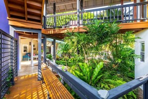 A multi-level outdoor area with a wooden deck, a balcony, and lush greenery.