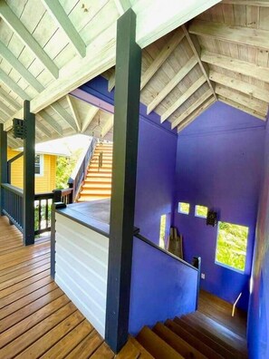 A covered wooden deck with a staircase leading to a second level.