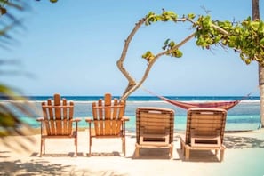Une scène de plage avec des chaises en bois et un hamac.