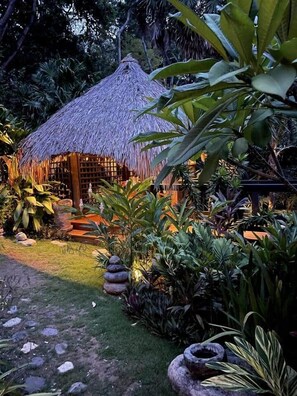 A thatched-roof structure surrounded by lush tropical vegetation.