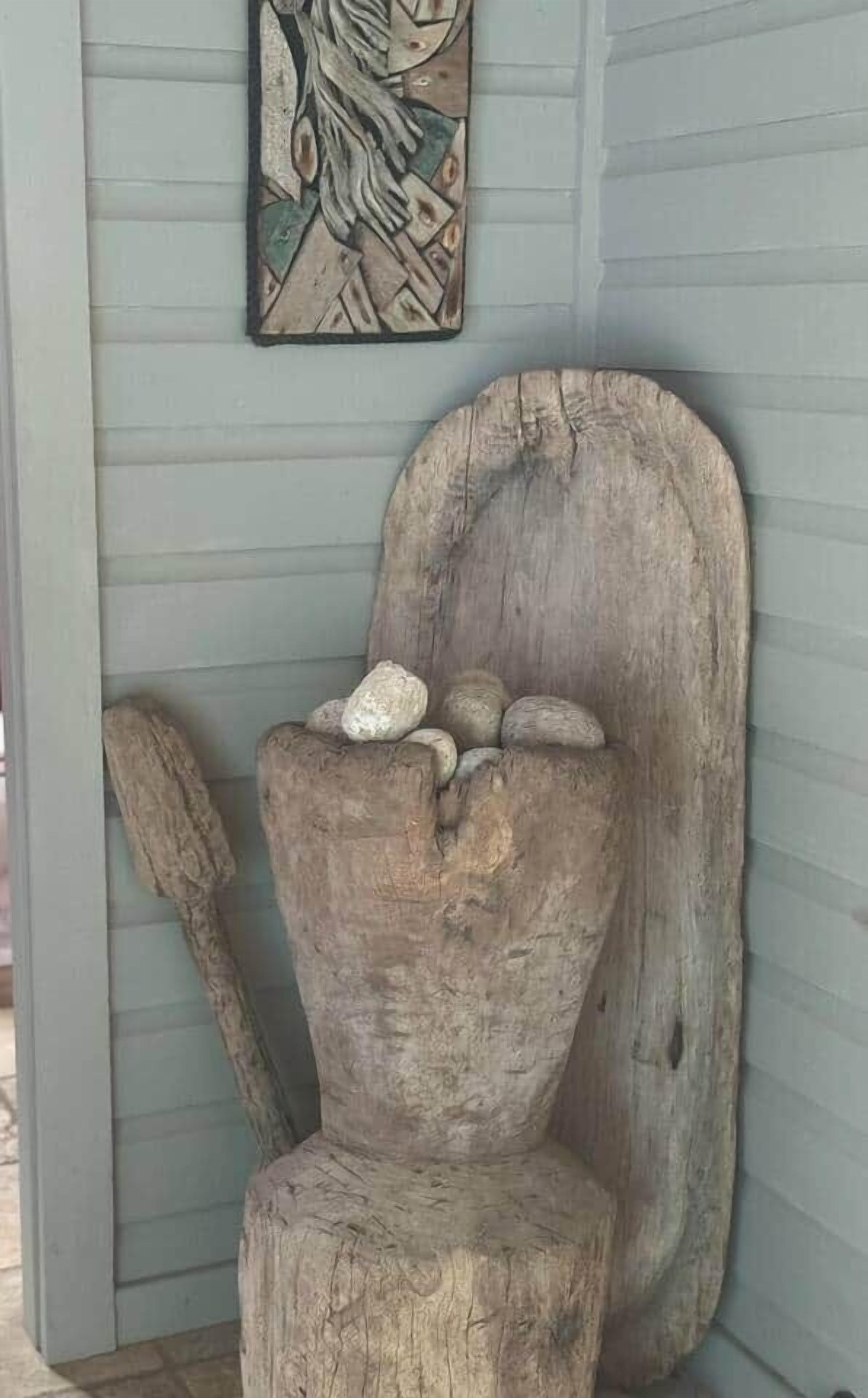 Ein rustikaler Holzstuhl mit hoher Rückenlehne und kleiner Sitzfläche, an einer Wand mit horizontaler Holzverkleidung platziert.