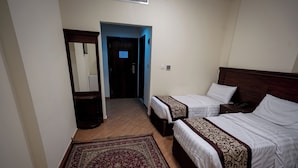 Une chambre d’hôtel avec deux lits, un plancher en bois, un tapis rouge à motifs et un miroir.