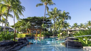 A pool area with clear water, surrounded by rocks and palm trees. - Luxury Living with Pool Access (Kamuela)