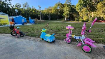 Un área de concreto con tres triciclos infantiles, incluyendo uno rojo.