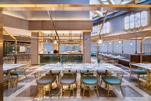 A modern restaurant interior with high ceilings, tiered seating, and a central bar area. - Crystal Orange Hotel Qingdao Jimo Heshan Road (Qingdao)