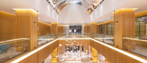 A modern interior with a central atrium, glass railings, and a ceiling with abstract designs.