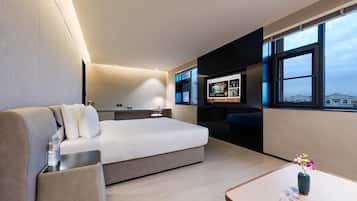 Una habitación de hotel moderna con una cama, un escritorio, un televisor y vistas a la ciudad.