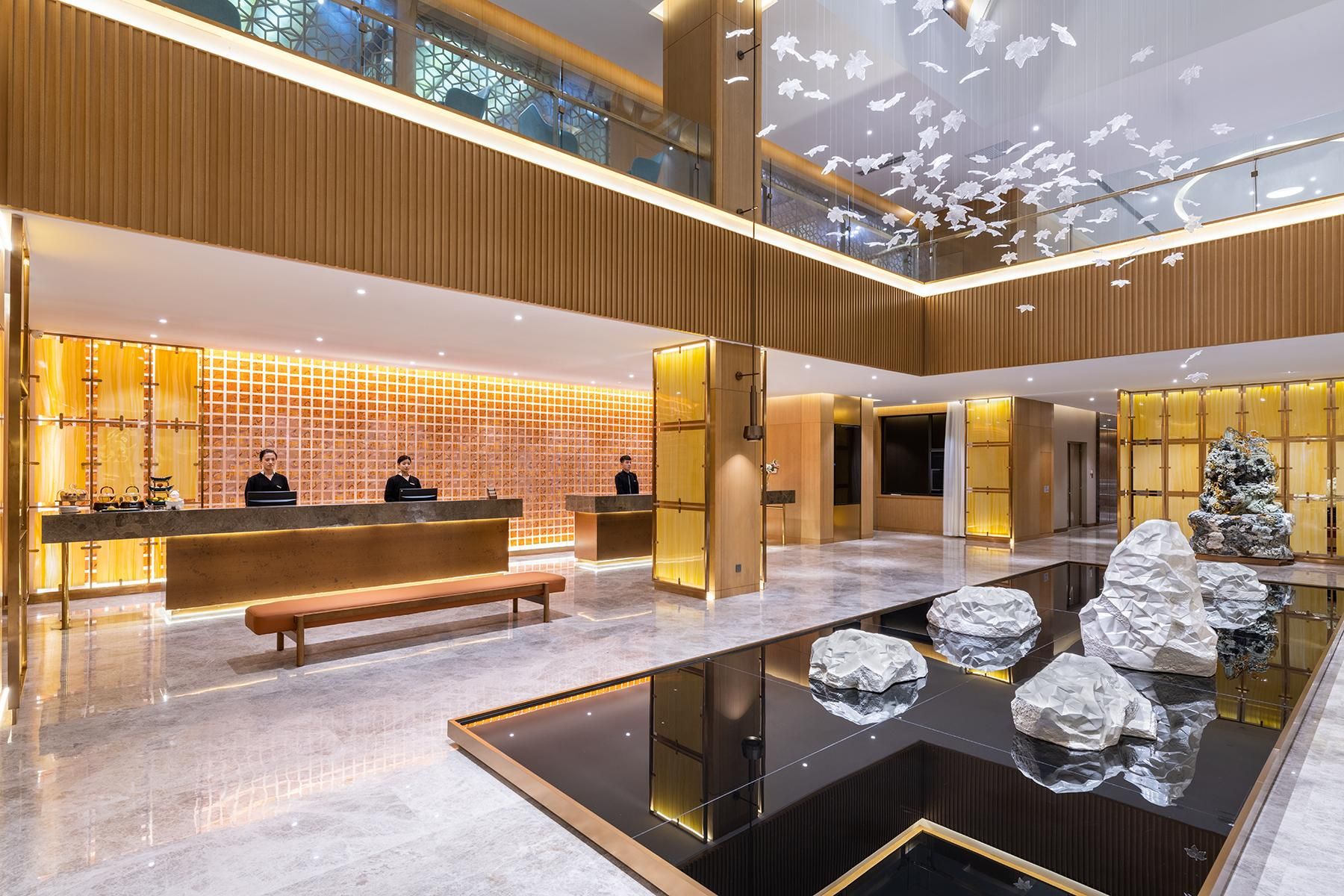 Un vestíbulo de hotel moderno con mostrador de recepción, zona de estar y una fuente decorativa.