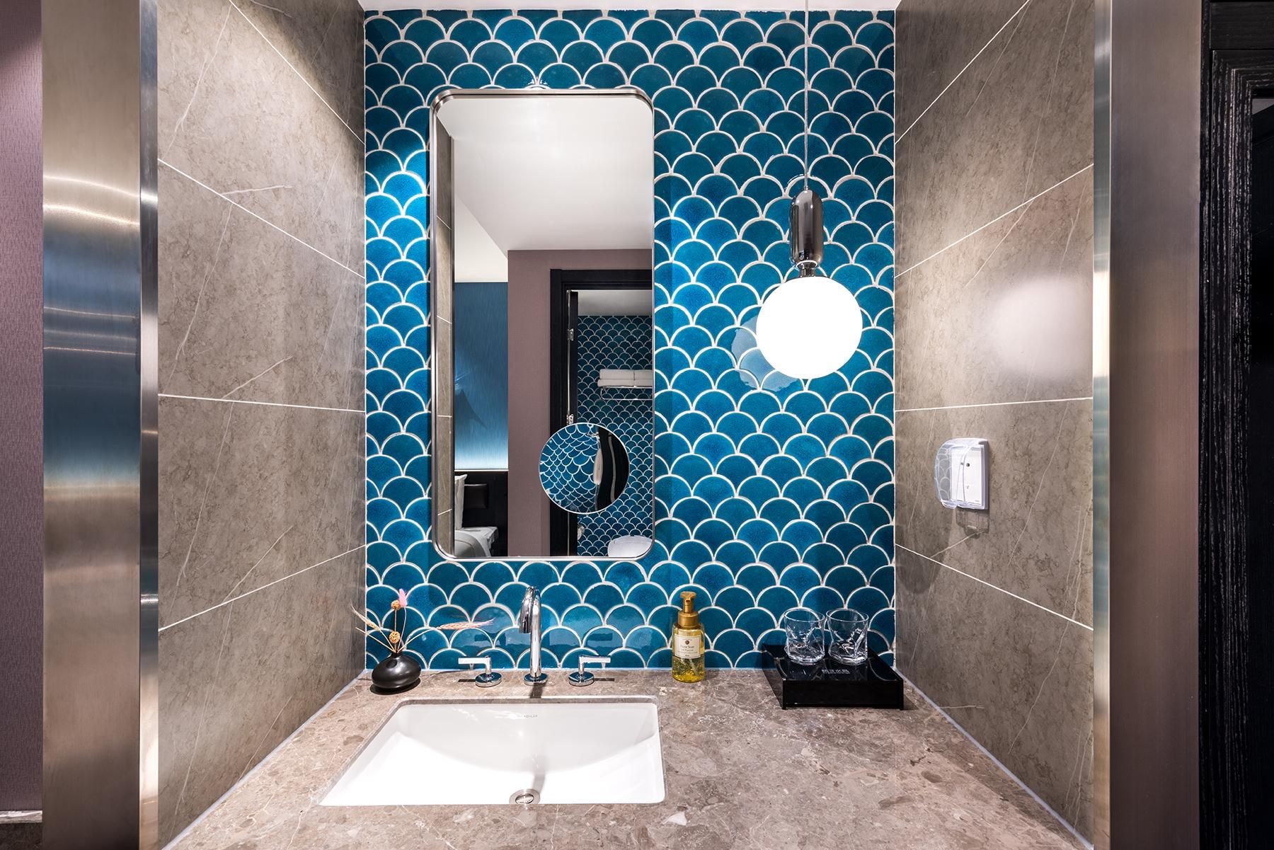 Un baño con un espejo grande, un lavamanos y un papel tapiz decorativo.