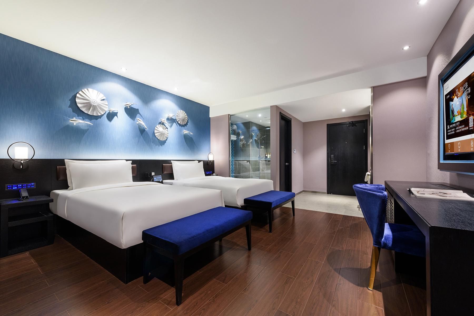 Habitación de hotel con dos camas, un escritorio y una televisión.