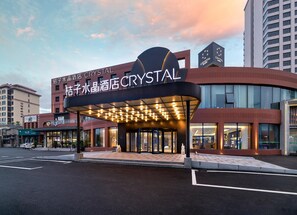 A hotel named 'Crystal' with a modern design, featuring a prominent curved entrance and illuminated signage. - Crystal Orange Hotel Qingdao Jimo Heshan Road (Qingdao)