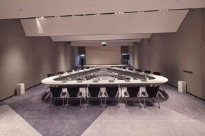 A conference room with a round table, chairs, and a projector screen. - Blossom Hill Hotel Yangzhou Slender West Lake (Yangzhou)