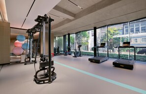 A modern gym with exercise equipment, large windows, and a view of the city. - Blossom Hill Hotel Yangzhou Slender West Lake (Yangzhou)