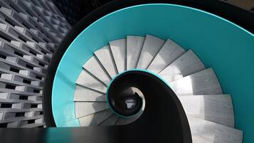 Una escalera de caracol con escalones verde azulado y blancos, que ascienden.