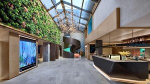 Un intérieur moderne avec un mur vert, une structure noire aux lignes courbes et un espace bar avec des bouteilles.