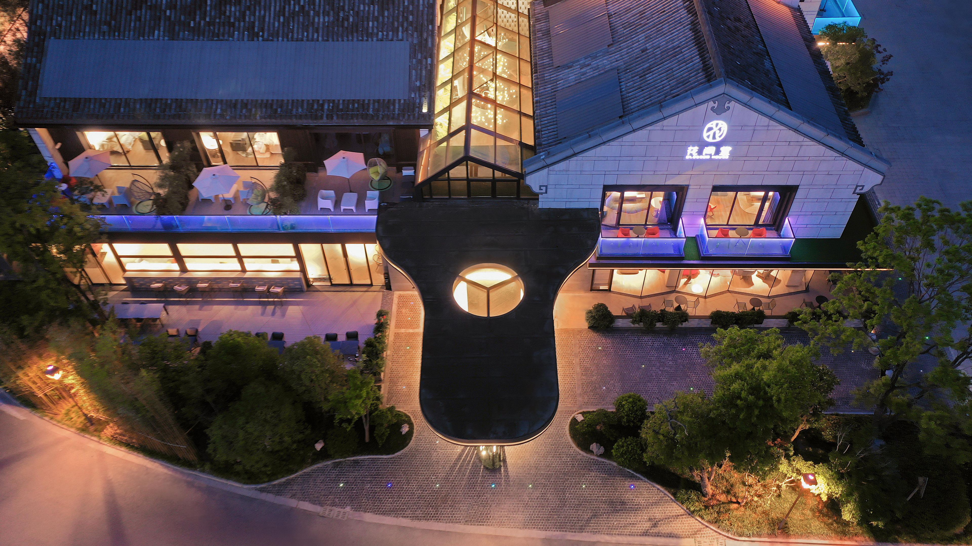 A modern building with a glass facade, outdoor seating area, and a distinctive central feature.