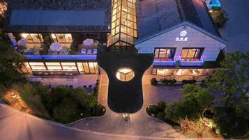 A modern building with a glass facade, outdoor seating area, and a distinctive central feature.