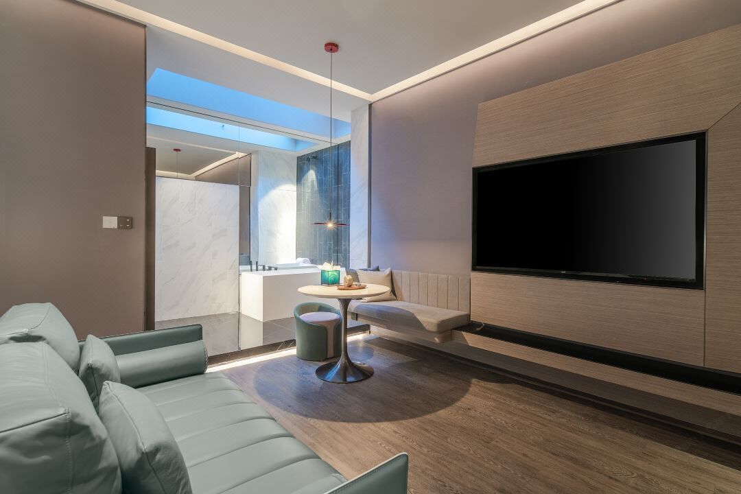 A modern living room with a sofa, a coffee table, and a flat-screen TV mounted on the wall.