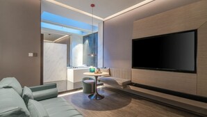 A modern living room with a sofa, a coffee table, and a flat-screen TV mounted on the wall. - Blossom Hill Hotel Yangzhou Slender West Lake (Yangzhou)