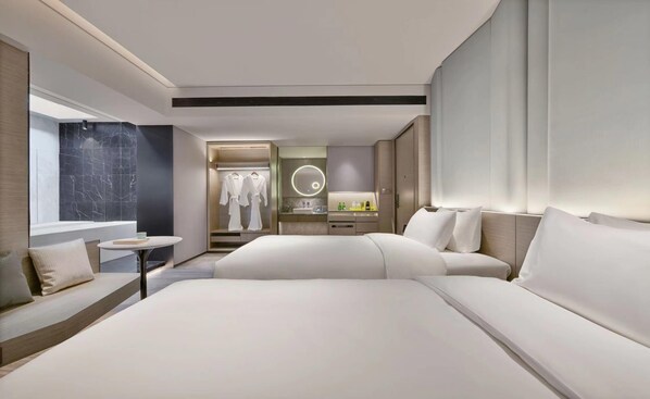 A modern hotel room with a large bed, a sitting area with a small table, and a bathroom with a vanity and mirror. - Blossom Hill Hotel Yangzhou Slender West Lake (Yangzhou)