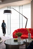 A modern interior with a red sofa, two glass vases with plants, and a round glass table.