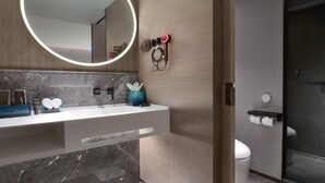 A modern bathroom with a marble vanity, a large mirror with a circular light, a toilet, and a shower area. - Blossom Hill Hotel Yangzhou Slender West Lake (Yangzhou)