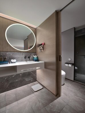 A modern bathroom with a marble vanity, a large mirror with a circular light, a toilet, and a shower area. - Blossom Hill Hotel Yangzhou Slender West Lake (Yangzhou)