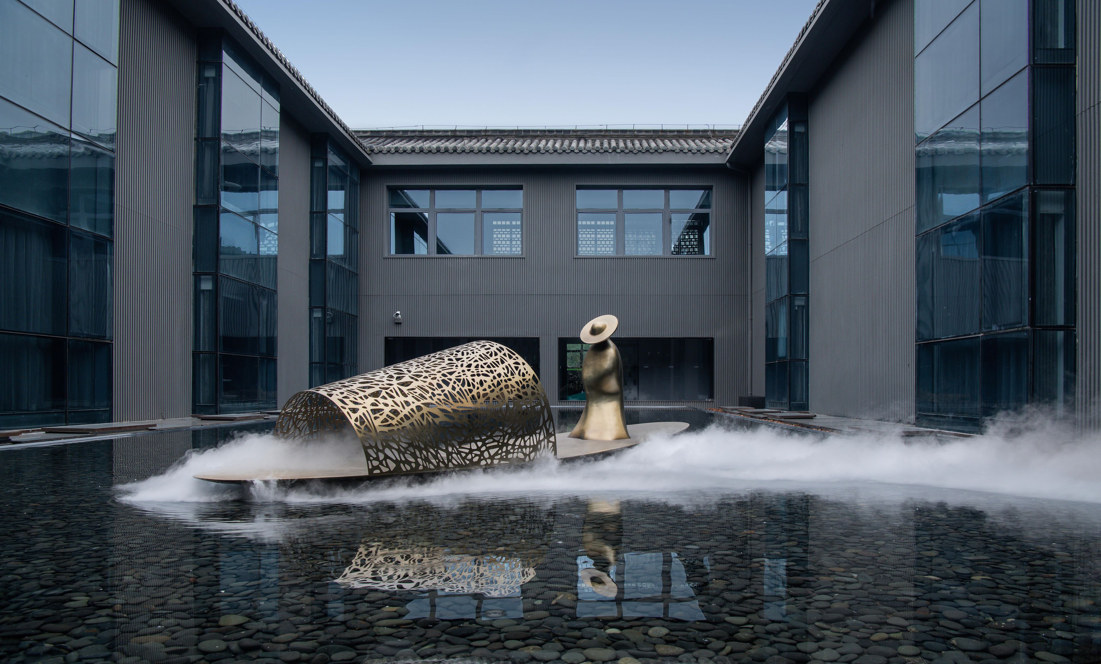 A modern building with a reflective water feature in front.