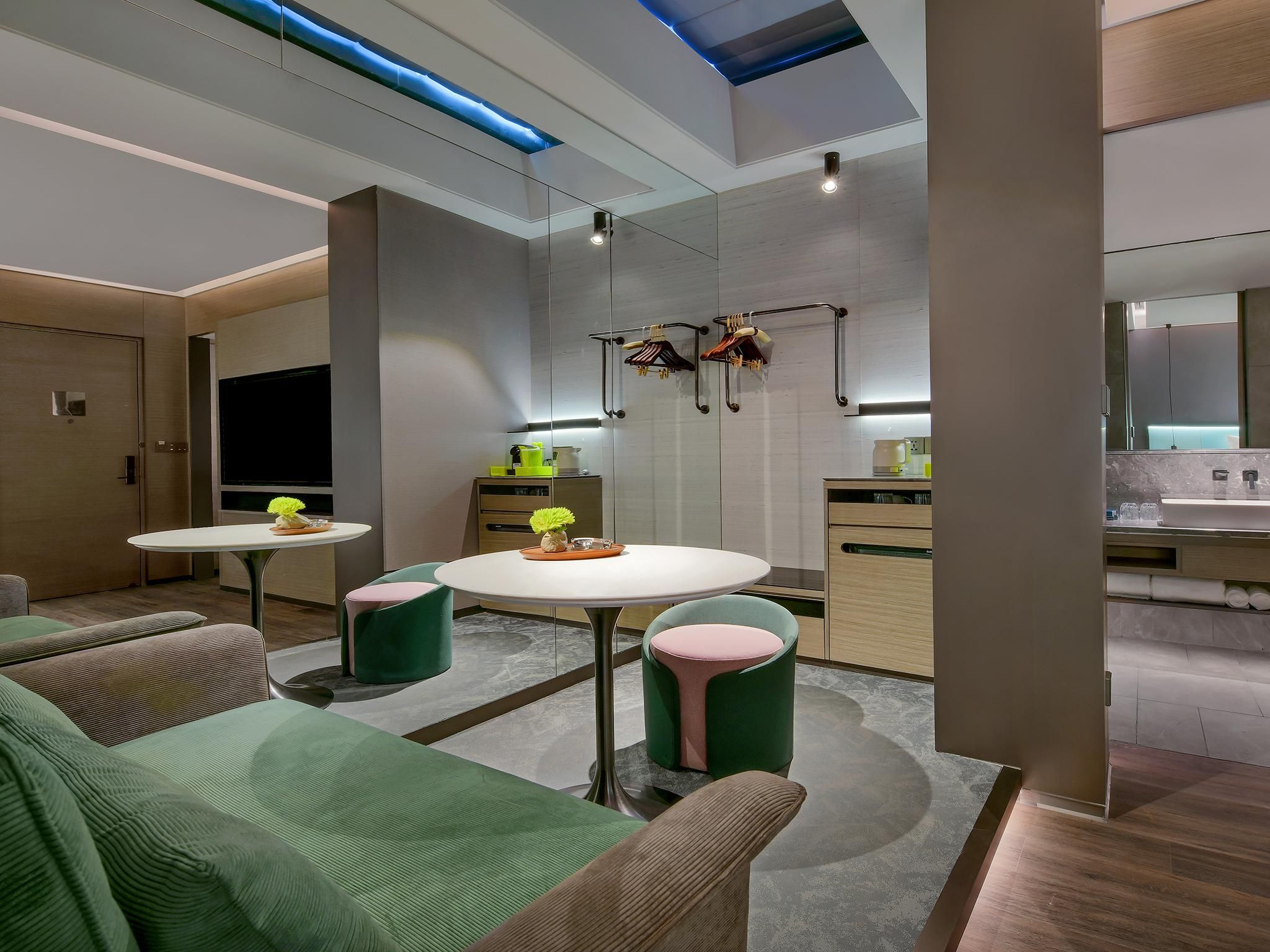 A modern kitchen with a central island, built-in appliances, and a dining area with green upholstered chairs.
