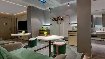 A modern kitchen with a central island, built-in appliances, and a dining area with green upholstered chairs.