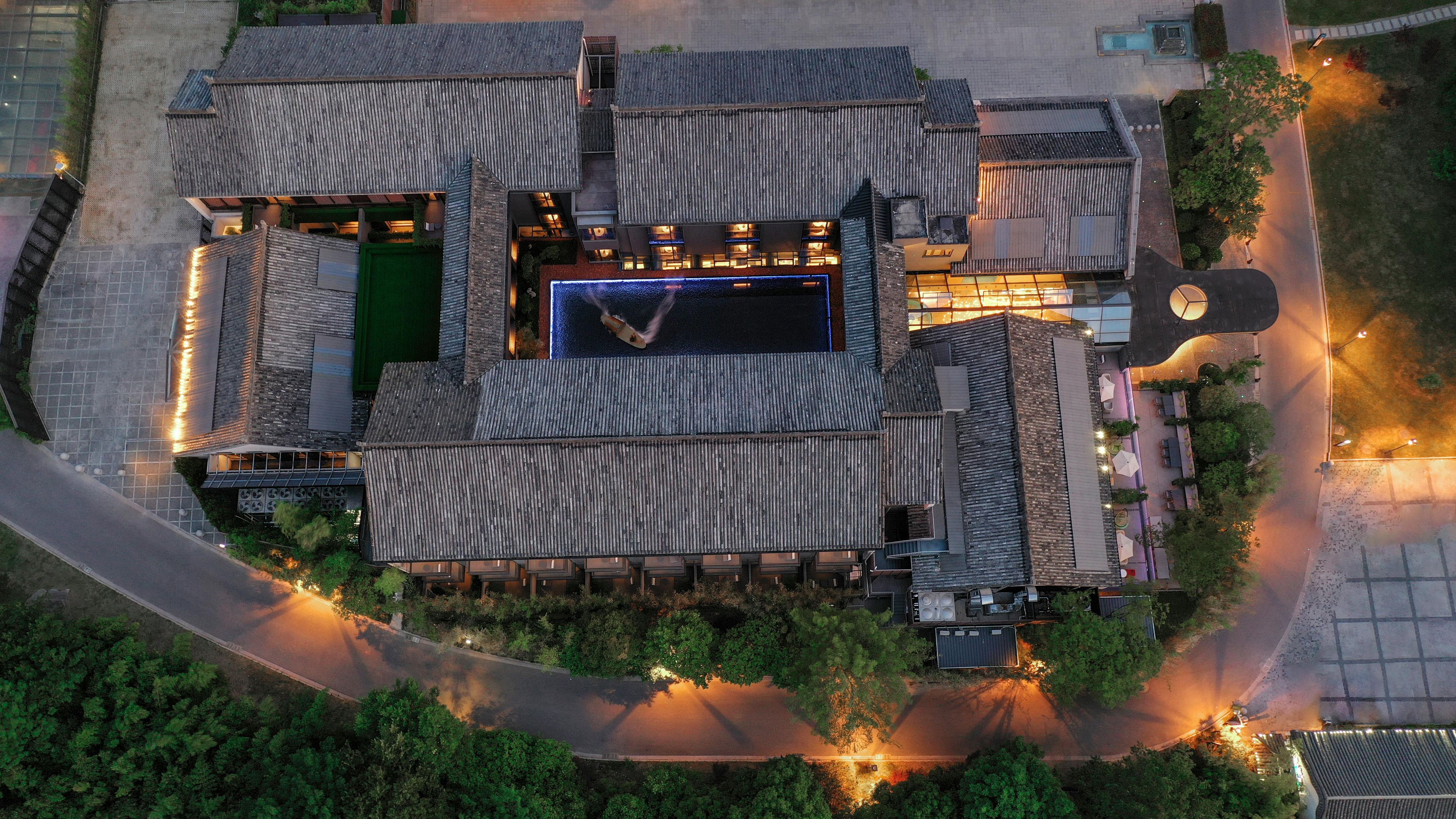 An aerial view of a hotel with a central courtyard, multiple buildings with traditional roofing, and surrounding greenery.
