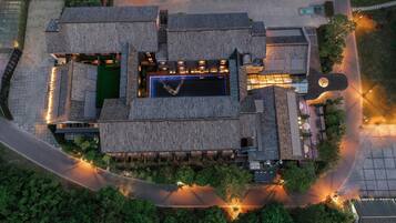 An aerial view of a hotel with a central courtyard, multiple buildings with traditional roofing, and surrounding greenery.