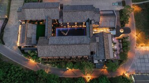 An aerial view of a hotel with a central courtyard, multiple buildings with traditional roofing, and surrounding greenery. - Blossom Hill Hotel Yangzhou Slender West Lake (Yangzhou)