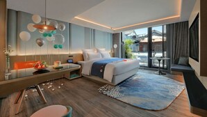 A modern hotel room with a large bed, a desk, a dining table, and a view of the outside. - Blossom Hill Hotel Yangzhou Slender West Lake (Yangzhou)