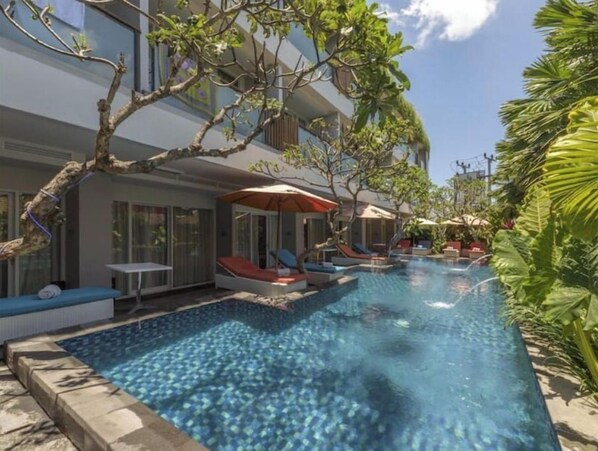 Relax by the serene pool surrounded by lush greenery and comfortable lounge chairs.