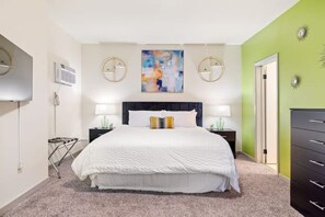 Relax in this serene bedroom with a large bed, bedside tables, and a beautiful abstract painting above.